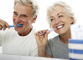 Older couple preventing dental emergencies in Acworth by brushing