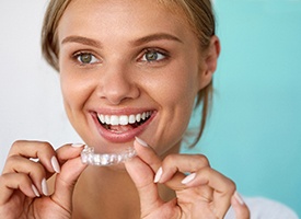 Woman smiling while holding whitening tray