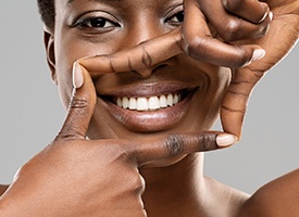 Woman smiling while framing her teeth with her fingers